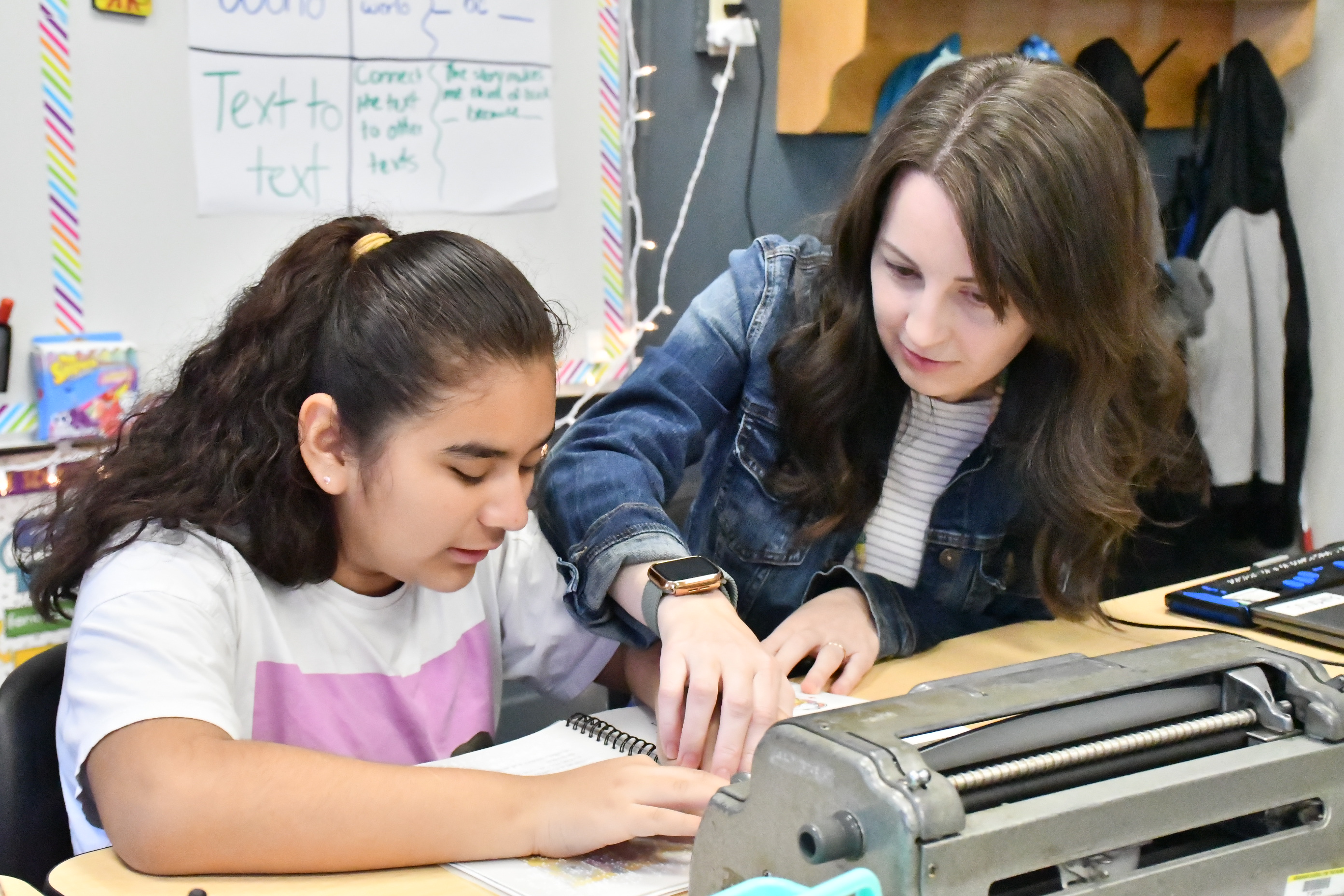 A teacher assists a student in reading braille.