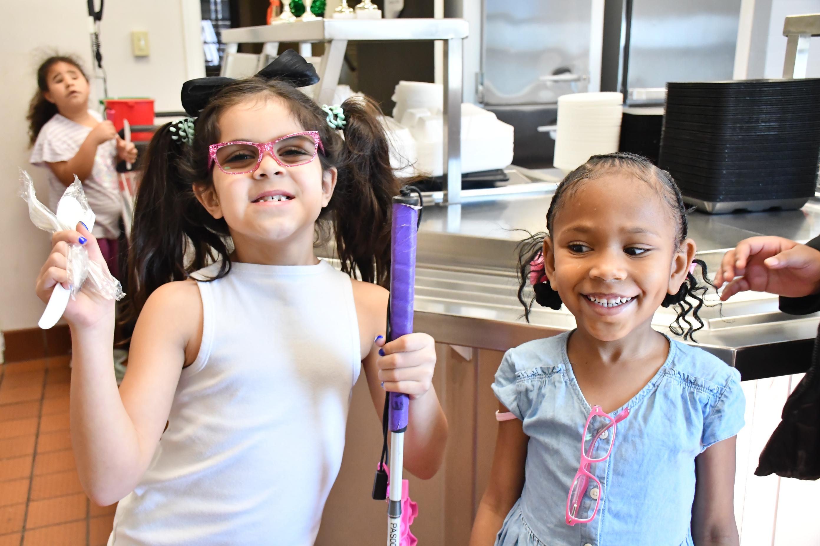 Two young girls smile in the cafeteria.