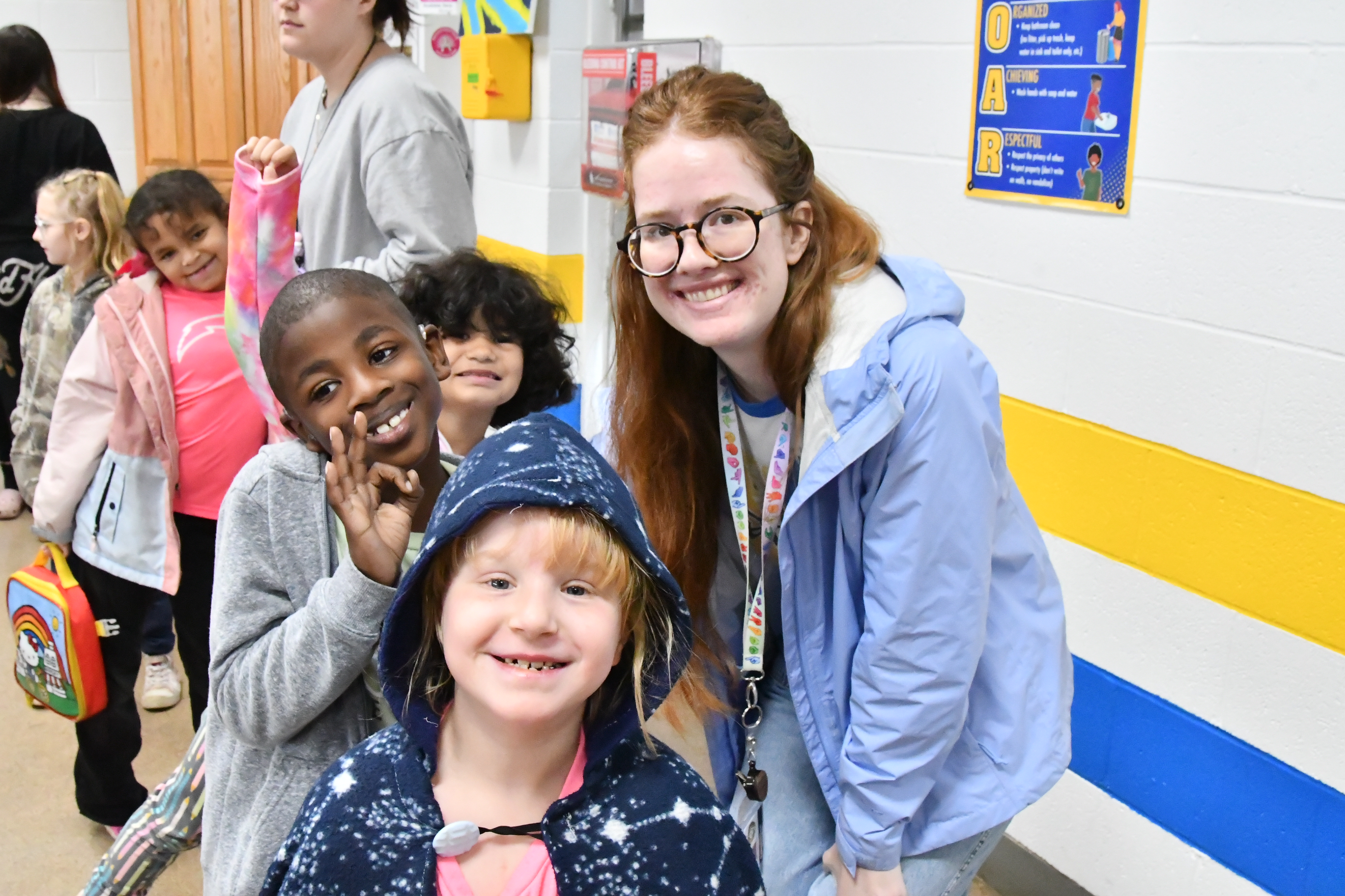 A teacher poses in the cafeteria with three students, all of whom smiling.